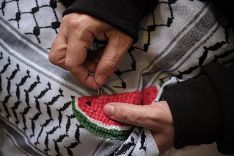 A woman cross-stitches a watermelon motif, a symbol of Palestinian resitance, onto a kuffiyeh at the Inaash center in Beirut. Jan. 9, 2024. (Credit: João Sousa/L'Orient Today)